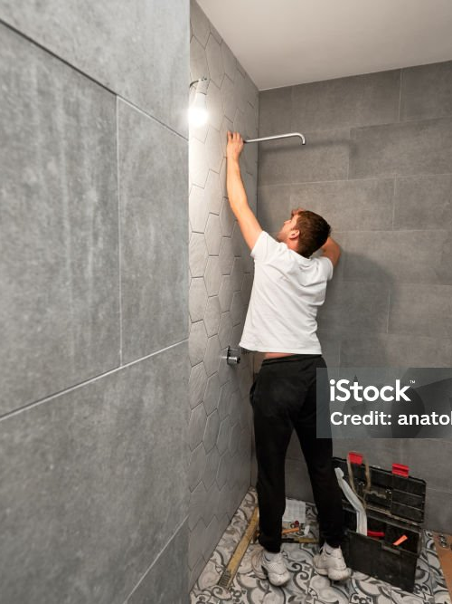 Fliesenleger bei der Arbeit in einer neu gefliesten Dusche